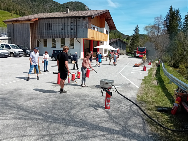 Besucher probieren Feuerlöscher unter Anleitung auf dem Parkplatz vor dem Feuerwehrhaus